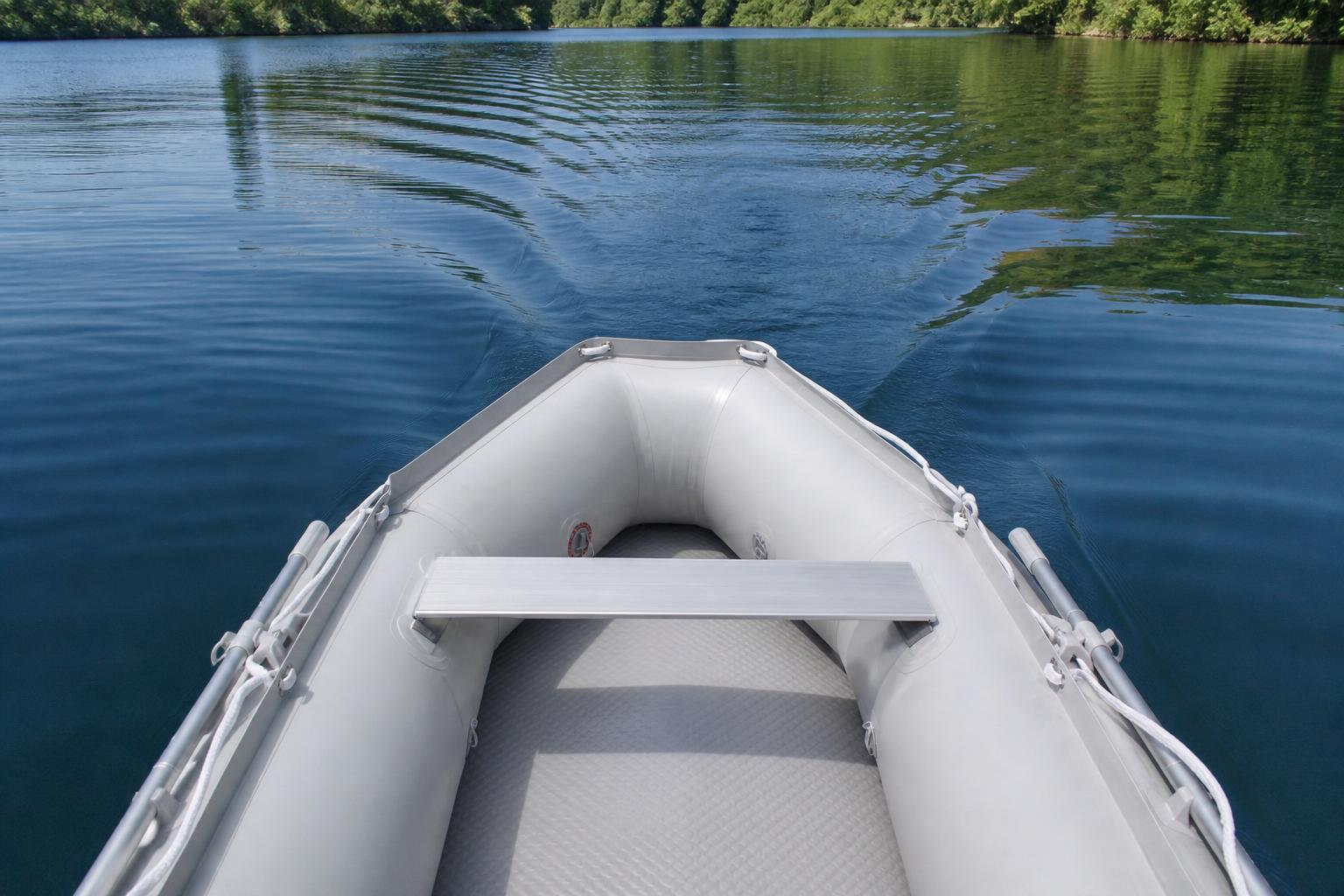 A paddler's point of view looking down at calm water with gentle ripples trailing behind an unseen small motor, peaceful
