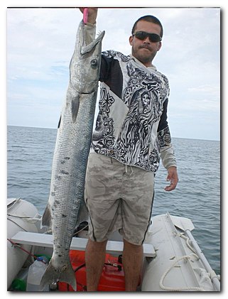 Picture of happy customer with barracuda he has caught while using Saturn inflatable boat.