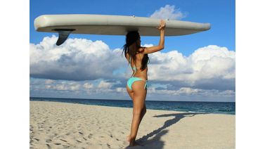 Girl carrying inflatable sup paddle board on a head